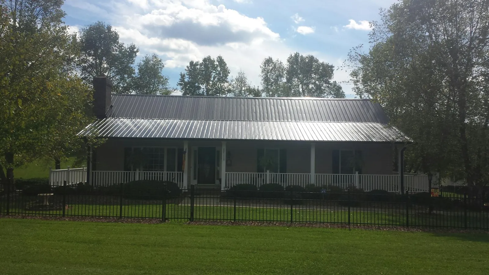 Gray metal roof on a brick ranch with a full width front porch — Gutter Guard Installation work by our crew in Bloomingdale